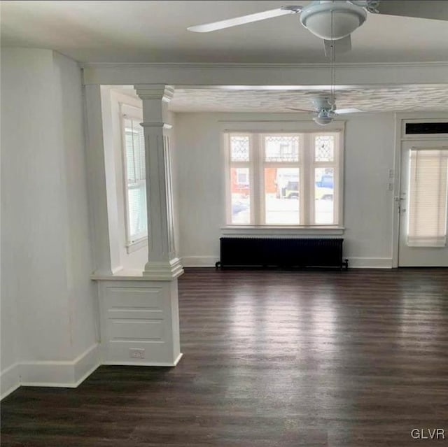 spare room with radiator, baseboards, dark wood-type flooring, and ornate columns