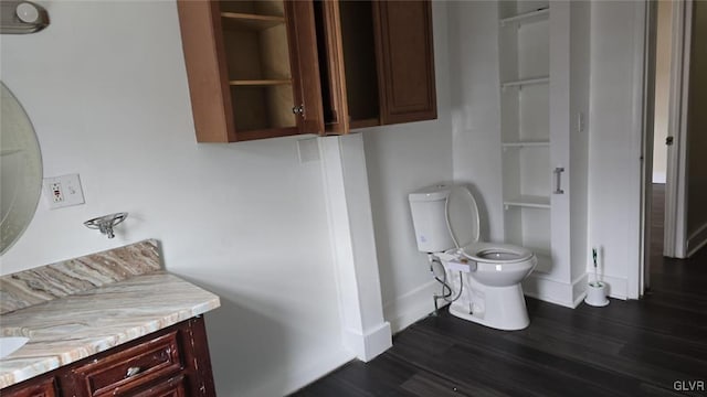 bathroom with vanity, toilet, wood finished floors, and baseboards