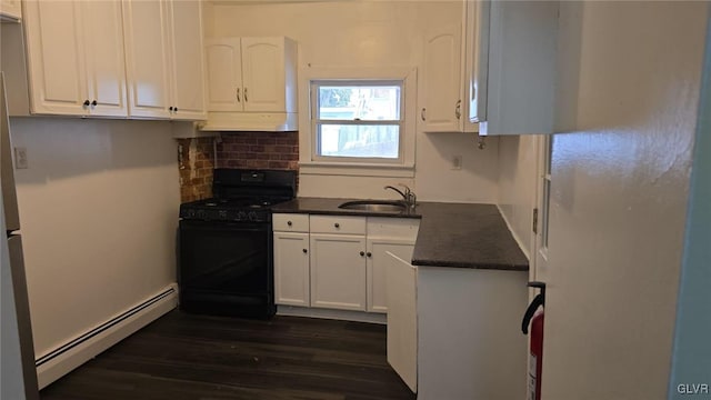 kitchen featuring dark countertops, a sink, under cabinet range hood, gas stove, and a baseboard radiator