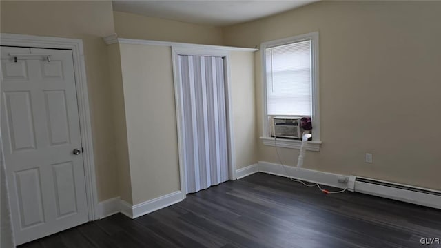 unfurnished bedroom with dark wood finished floors, baseboard heating, cooling unit, and baseboards