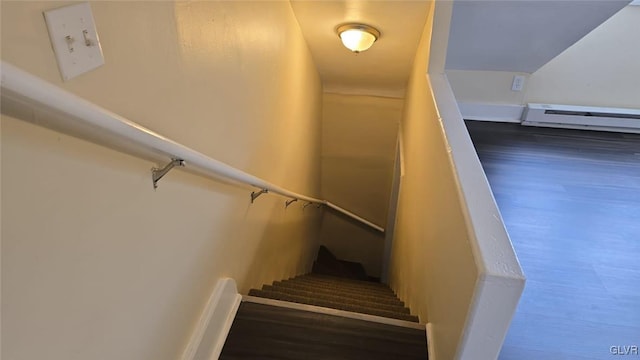 staircase with lofted ceiling, baseboard heating, and wood finished floors