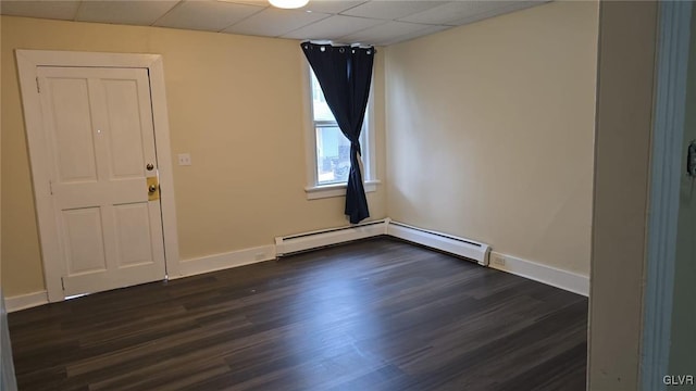 unfurnished room with dark wood-type flooring, baseboards, and a drop ceiling