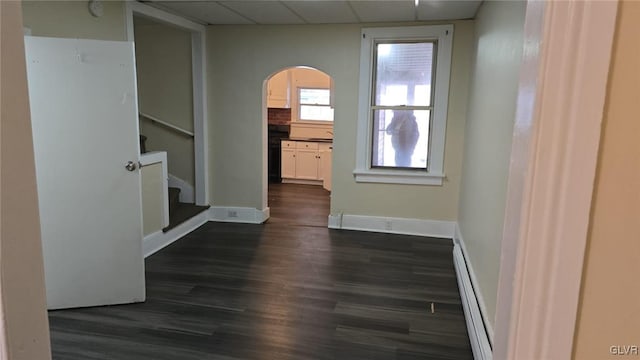 interior space featuring stairway, a baseboard radiator, arched walkways, a paneled ceiling, and dark wood-style flooring