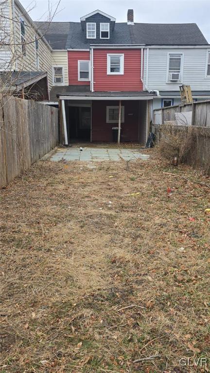 back of property featuring a chimney and fence