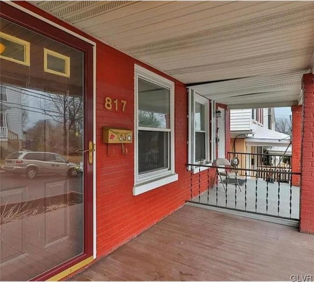 entrance to property with a porch and brick siding