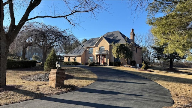 view of front of home featuring roof mounted solar panels, driveway, and a chimney