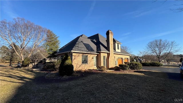 view of property exterior featuring brick siding, a chimney, and a lawn