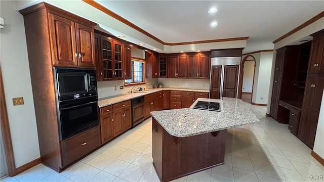 kitchen featuring a center island, black appliances, glass insert cabinets, and light stone countertops