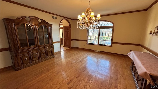 unfurnished dining area with arched walkways, visible vents, crown molding, and wood finished floors