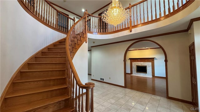 stairway featuring visible vents, baseboards, crown molding, and a towering ceiling