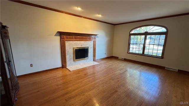 unfurnished living room with wood finished floors, a fireplace, visible vents, and baseboards