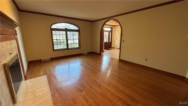 unfurnished living room with arched walkways, visible vents, light wood finished floors, and baseboards