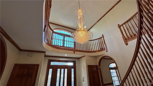 entryway featuring an inviting chandelier, stairway, and crown molding