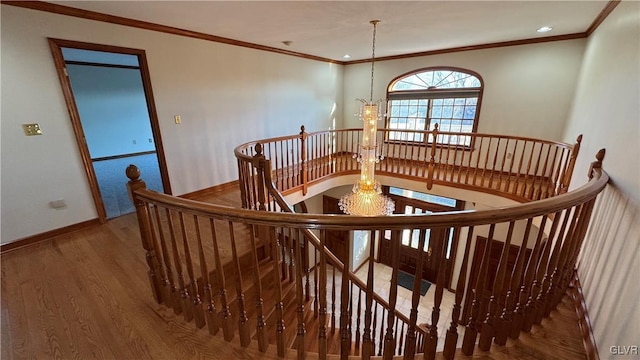 interior space featuring baseboards, wood finished floors, a chandelier, and crown molding