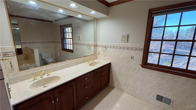 full bath with tile patterned floors, visible vents, double vanity, and a sink