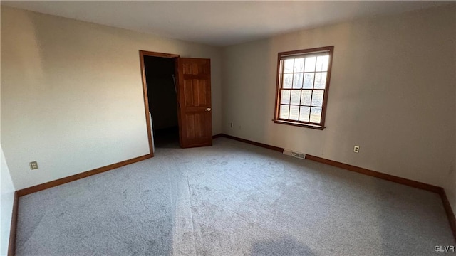 carpeted spare room featuring visible vents and baseboards