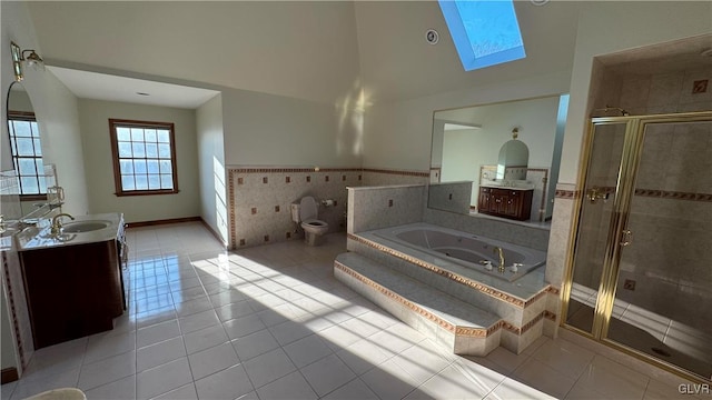 bathroom with tile patterned floors, lofted ceiling with skylight, a garden tub, a shower stall, and vanity