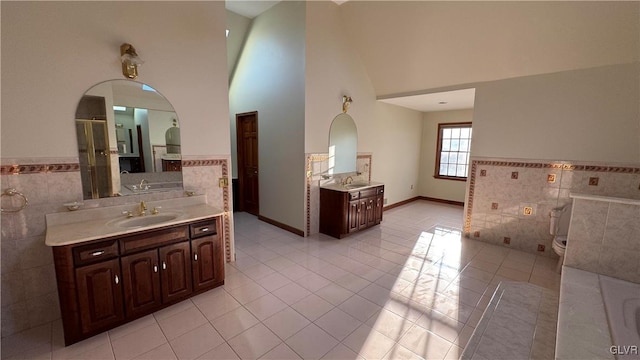 bathroom with tile patterned flooring, two vanities, a towering ceiling, tile walls, and a sink