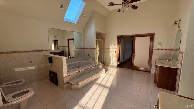 bathroom with tile patterned floors, wainscoting, a stall shower, and a skylight