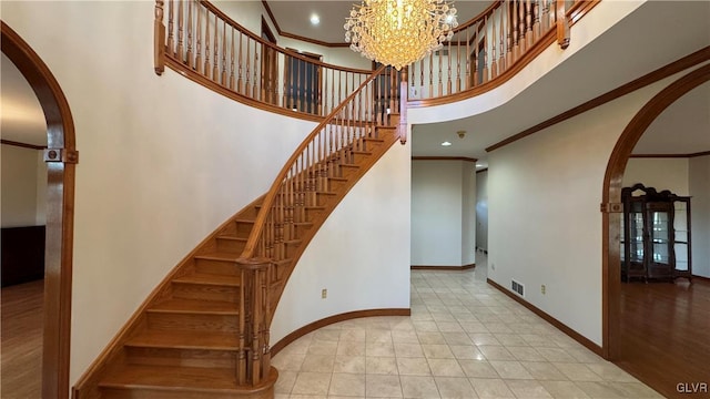 stairs featuring crown molding, a high ceiling, visible vents, and arched walkways