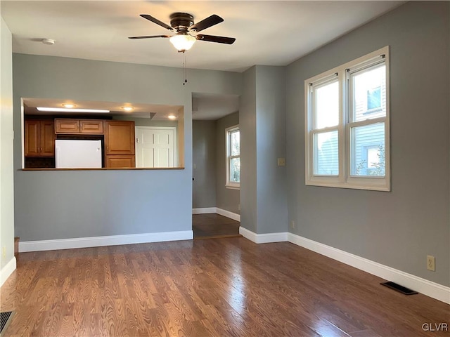 unfurnished living room featuring ceiling fan, dark wood-style floors, visible vents, and baseboards