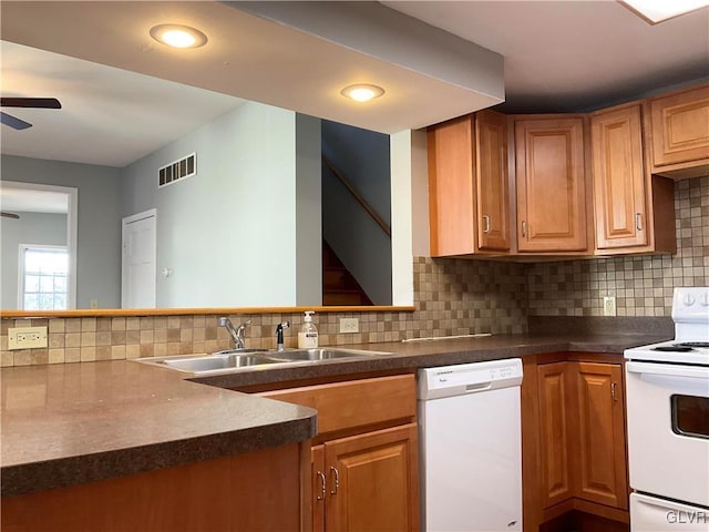 kitchen with dark countertops, visible vents, white appliances, a ceiling fan, and a sink