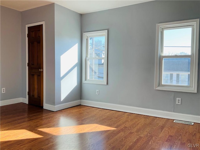 empty room with a wealth of natural light, baseboards, and wood finished floors