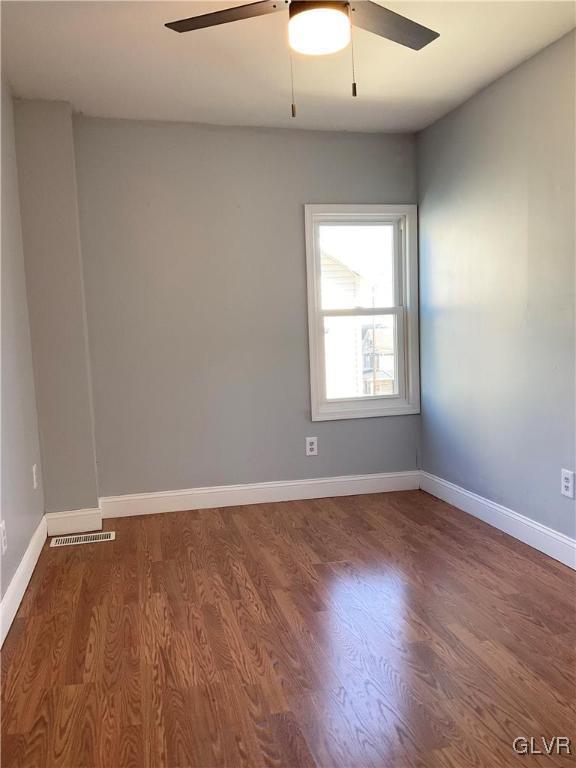 unfurnished room featuring visible vents, a ceiling fan, baseboards, and wood finished floors