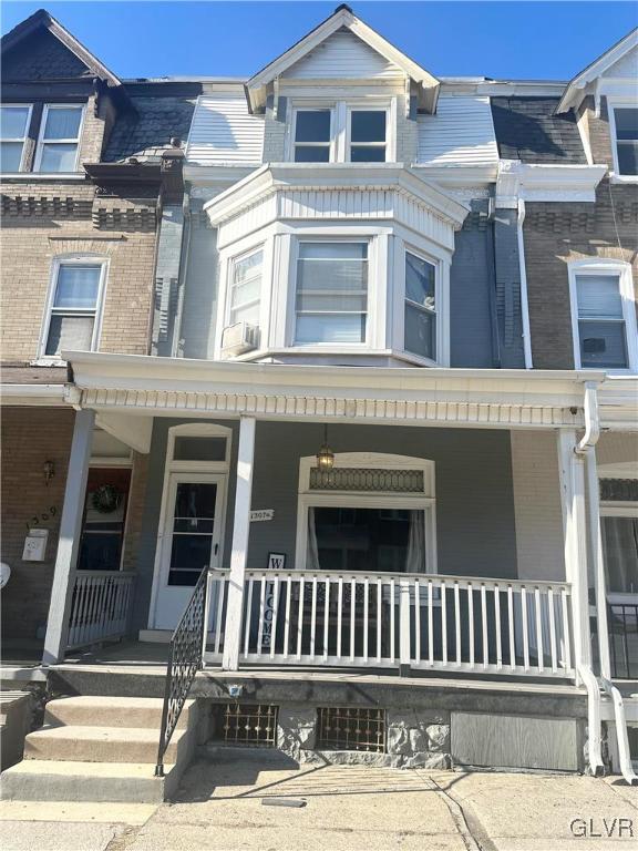 townhome / multi-family property with brick siding and covered porch