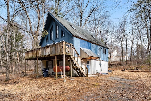 rear view of property featuring a wooden deck, roof with shingles, and stairs