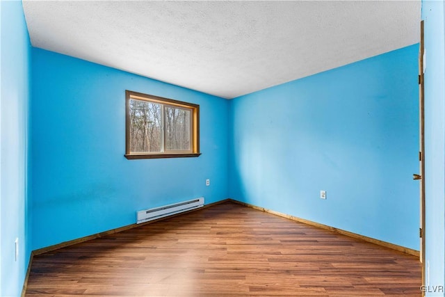 spare room featuring a baseboard radiator, baseboards, a textured ceiling, and wood finished floors