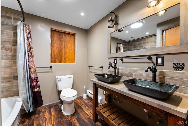 bathroom featuring toilet, wood finished floors, baseboards, and a sink