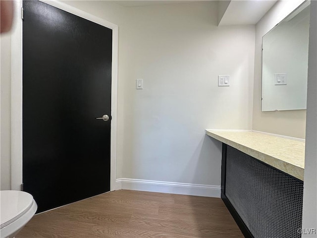 bathroom with toilet, wood finished floors, and baseboards