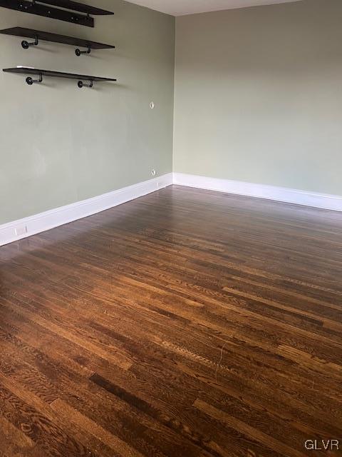 spare room featuring dark wood finished floors and baseboards