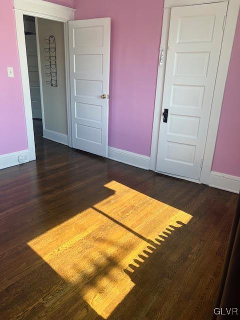 spare room featuring dark wood-type flooring and baseboards