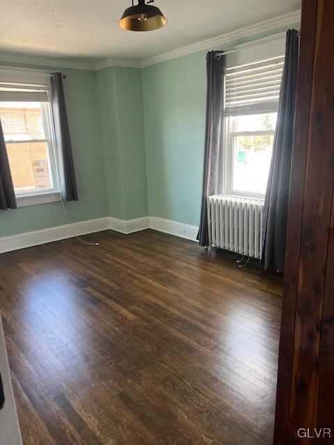 unfurnished room featuring baseboards, radiator, ornamental molding, and dark wood-style flooring