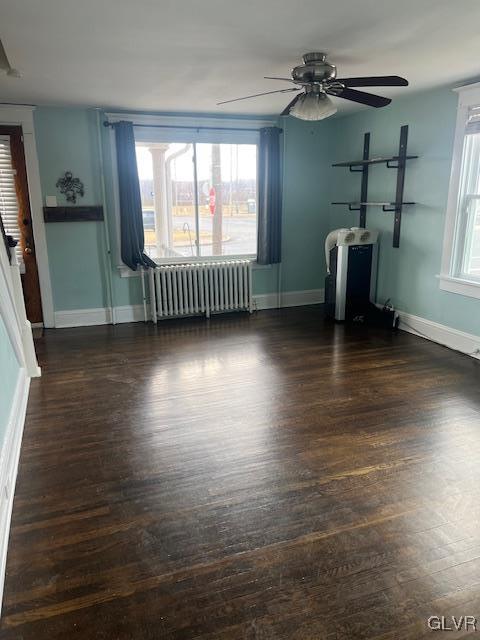 unfurnished living room with ceiling fan, radiator heating unit, baseboards, and wood finished floors