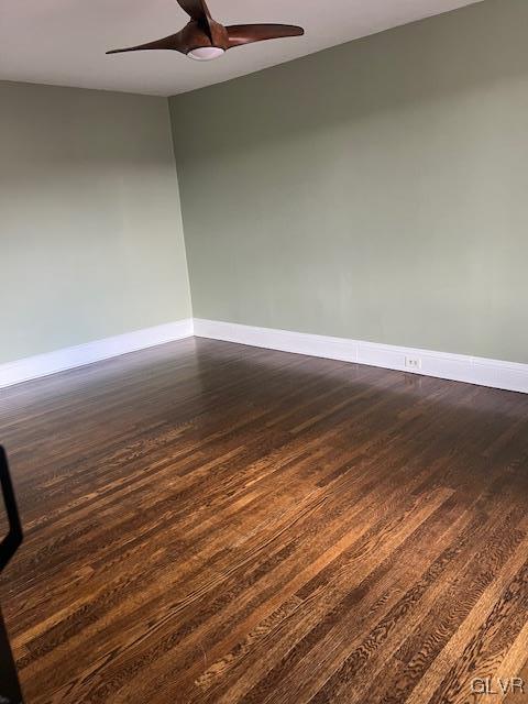 unfurnished room with a ceiling fan, dark wood-style flooring, and baseboards