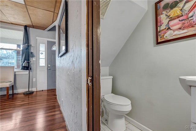 half bathroom featuring toilet, wood finished floors, and baseboards