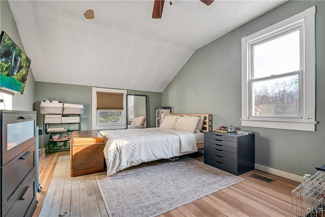 bedroom featuring a ceiling fan, visible vents, baseboards, vaulted ceiling, and light wood-style floors