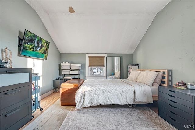 bedroom with vaulted ceiling, baseboards, and light wood-type flooring