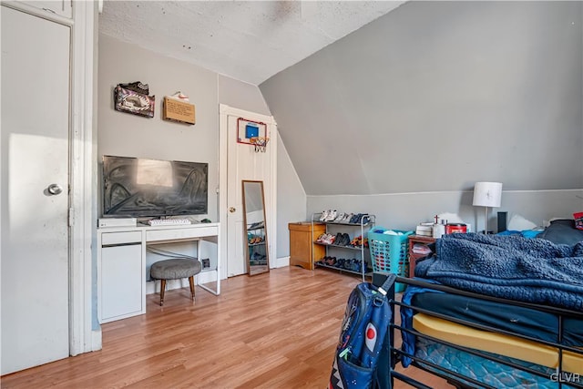 bedroom featuring light wood-style floors and vaulted ceiling