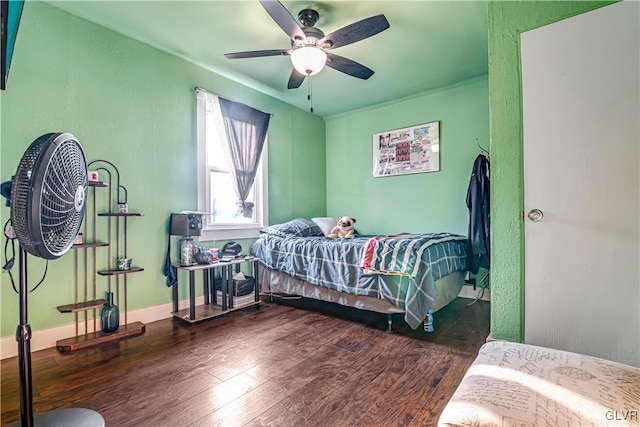 bedroom with ceiling fan, baseboards, wood finished floors, and a textured wall