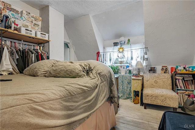 bedroom with a textured wall, wood-type flooring, and a textured ceiling