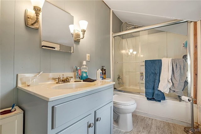 full bath featuring combined bath / shower with glass door, toilet, wood finished floors, and vanity