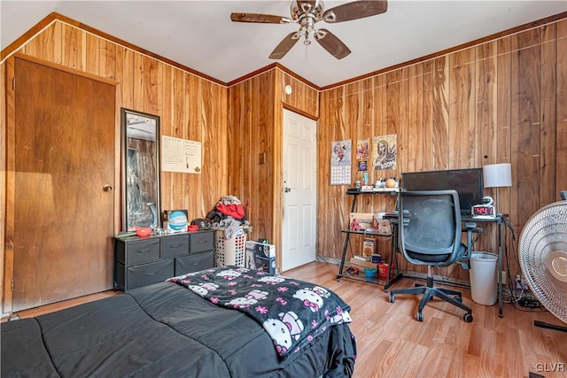 bedroom with wood walls, a ceiling fan, and wood finished floors