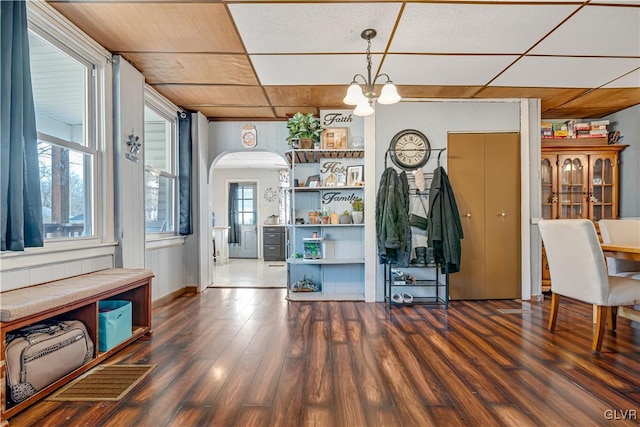 interior space featuring arched walkways, an inviting chandelier, and dark wood-style flooring