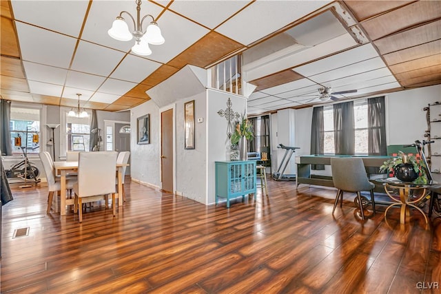 dining area featuring a drop ceiling, visible vents, wood finished floors, and ceiling fan with notable chandelier