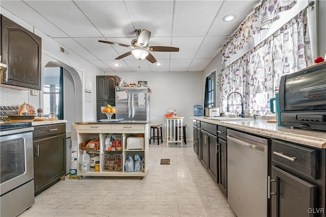 kitchen with visible vents, a sink, a drop ceiling, stainless steel appliances, and arched walkways