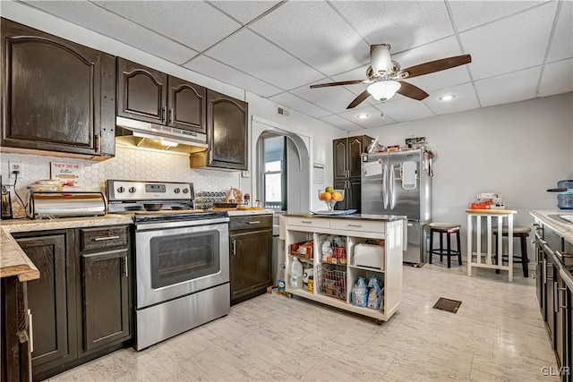 kitchen featuring dark brown cabinetry, appliances with stainless steel finishes, under cabinet range hood, and light countertops